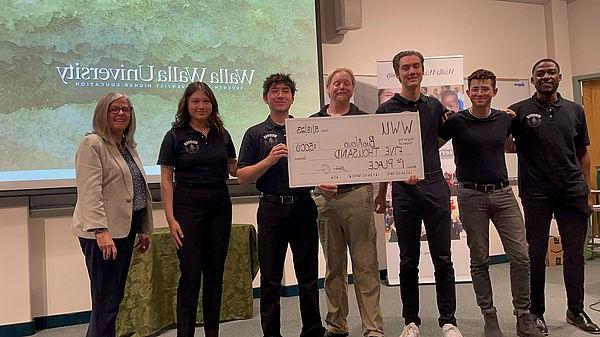 Photo of winning U-Pitch team with banner showing $5,000 win